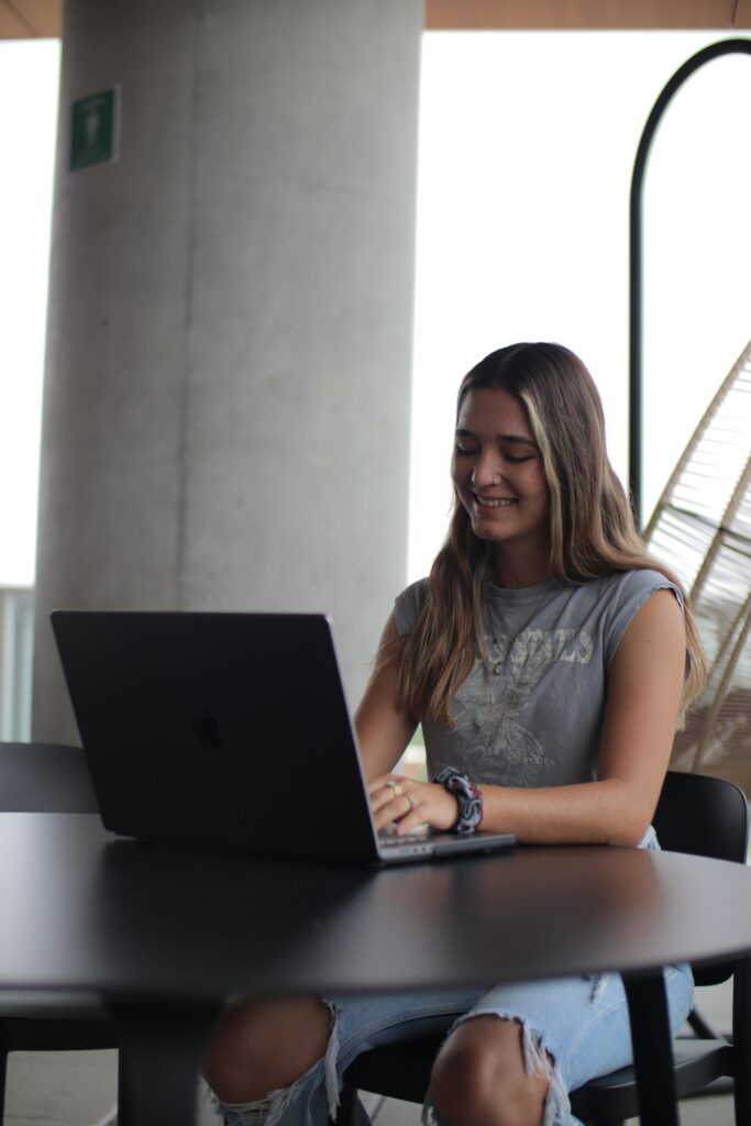 pexels-photo-17759542-17759542 Young woman using a laptop in a modern indoor setting, focused on online study.